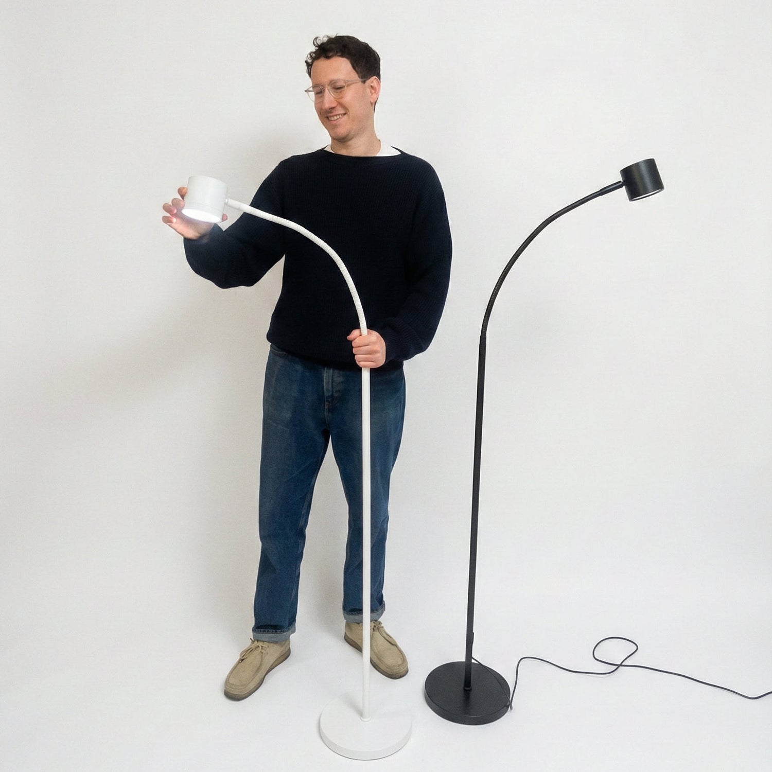 The founder holding a white floor lamp next to a black floor lamp on a white background